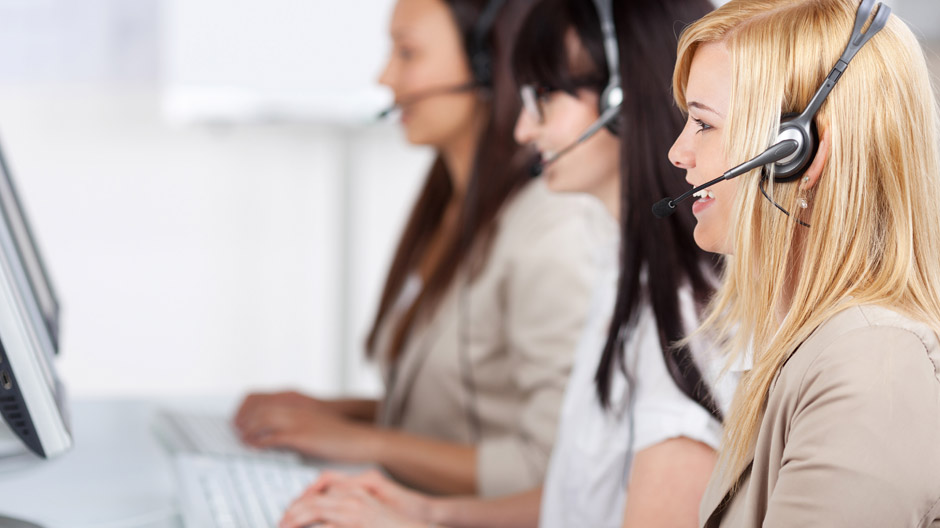 three young women sitting in the office using headset