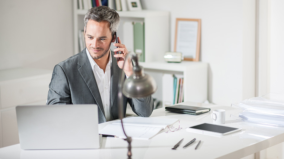 A businessman working at his desk using a smartphone.
