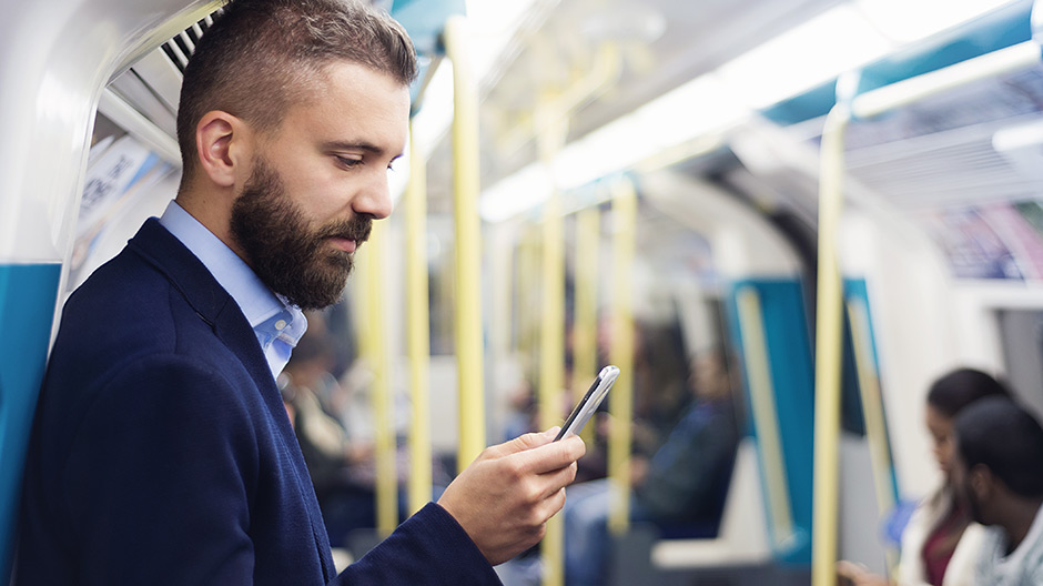 Man looking at his cellphone while using public transportation